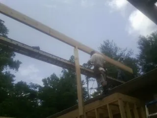 Carpenter setting a ridge beam over a new addition frame — Ice Dam Removal by Roofing Brothers in Crozier