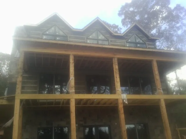 Dormers and porch framing on a large log home under construction — Roof Coating work by our crew in Crozier