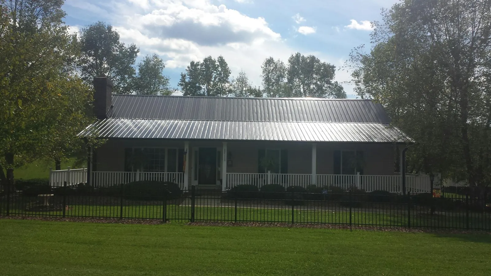 Gray metal roof on a brick ranch with a full width front porch — Gutter Guard Installation work by our crew in Crozier