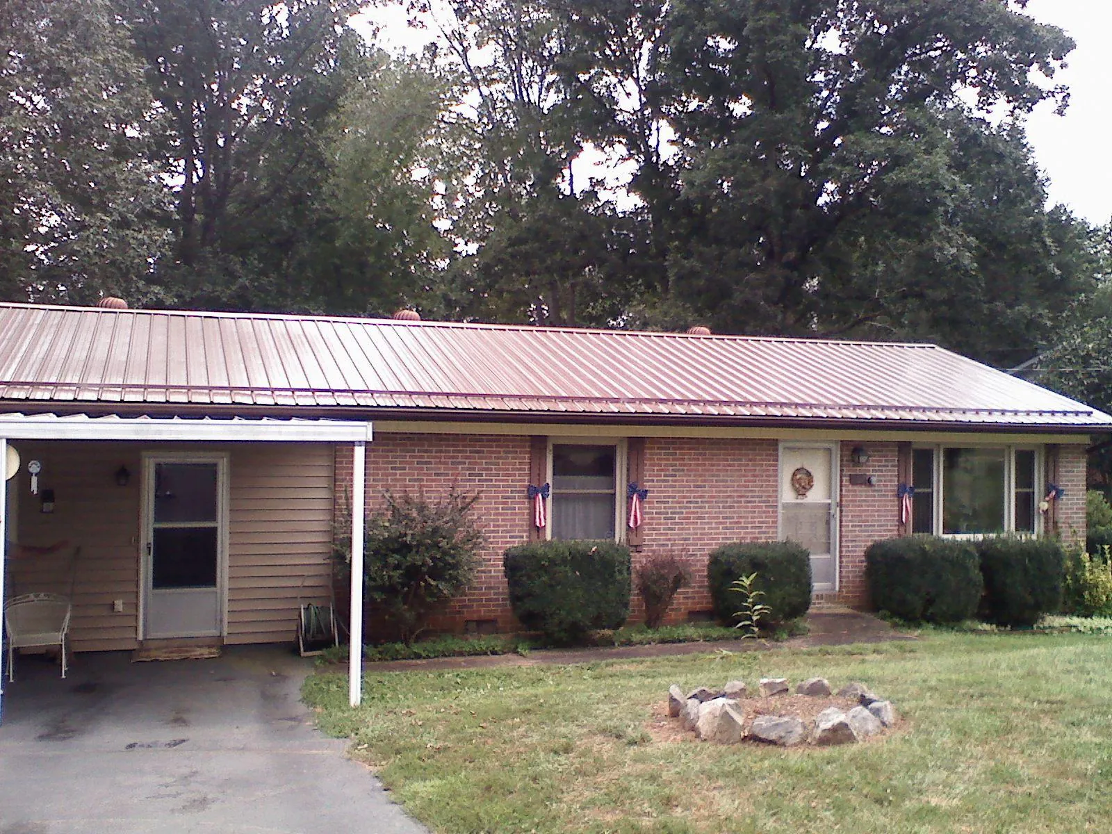 Bronze metal roof and carport on a brick ranch home — Roof Repair work by our crew in Crozier