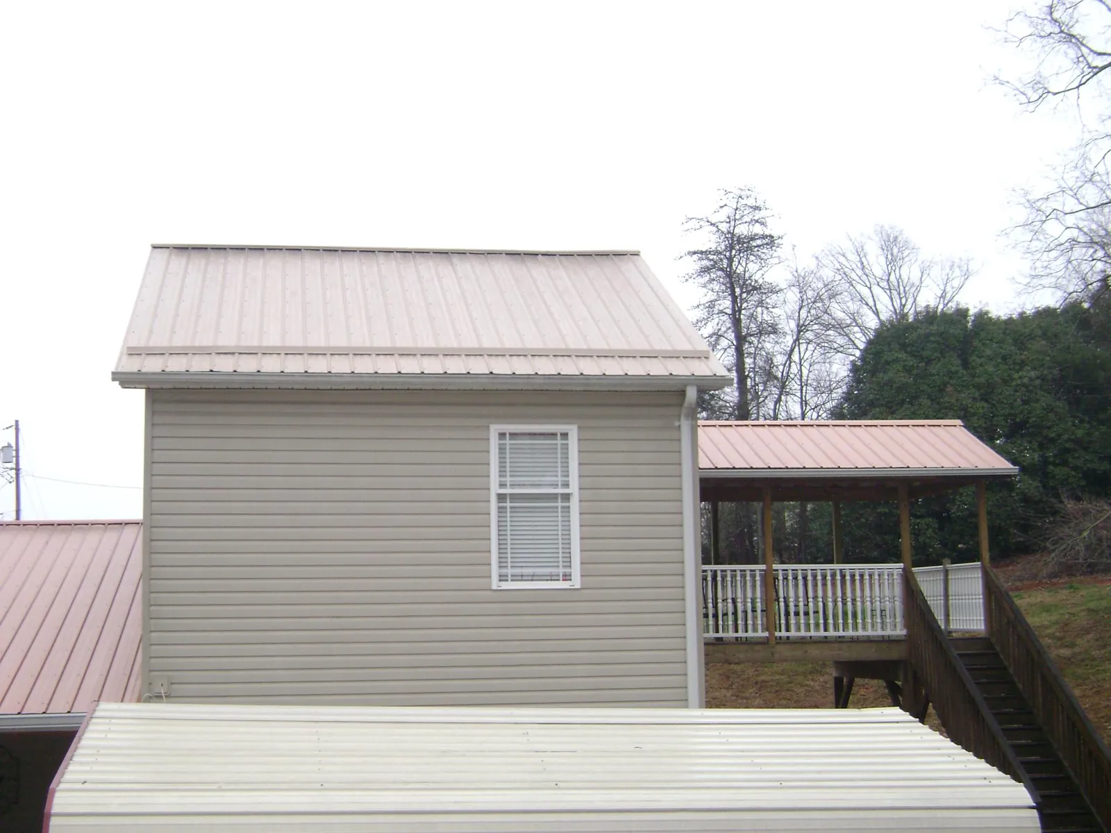Tan metal roofs on a two story addition and attached porch, from a Roof Replacement job in Crozier