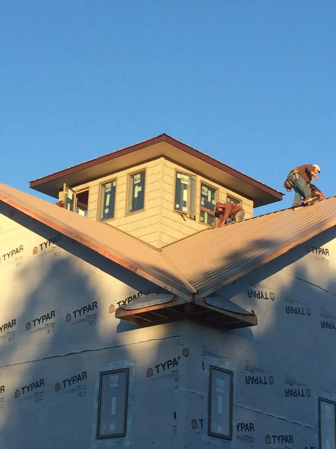 Roofers working around a rooftop cupola on a new metal roof at sunset — Roof Waterproofing in Crozier by Roofing Brothers